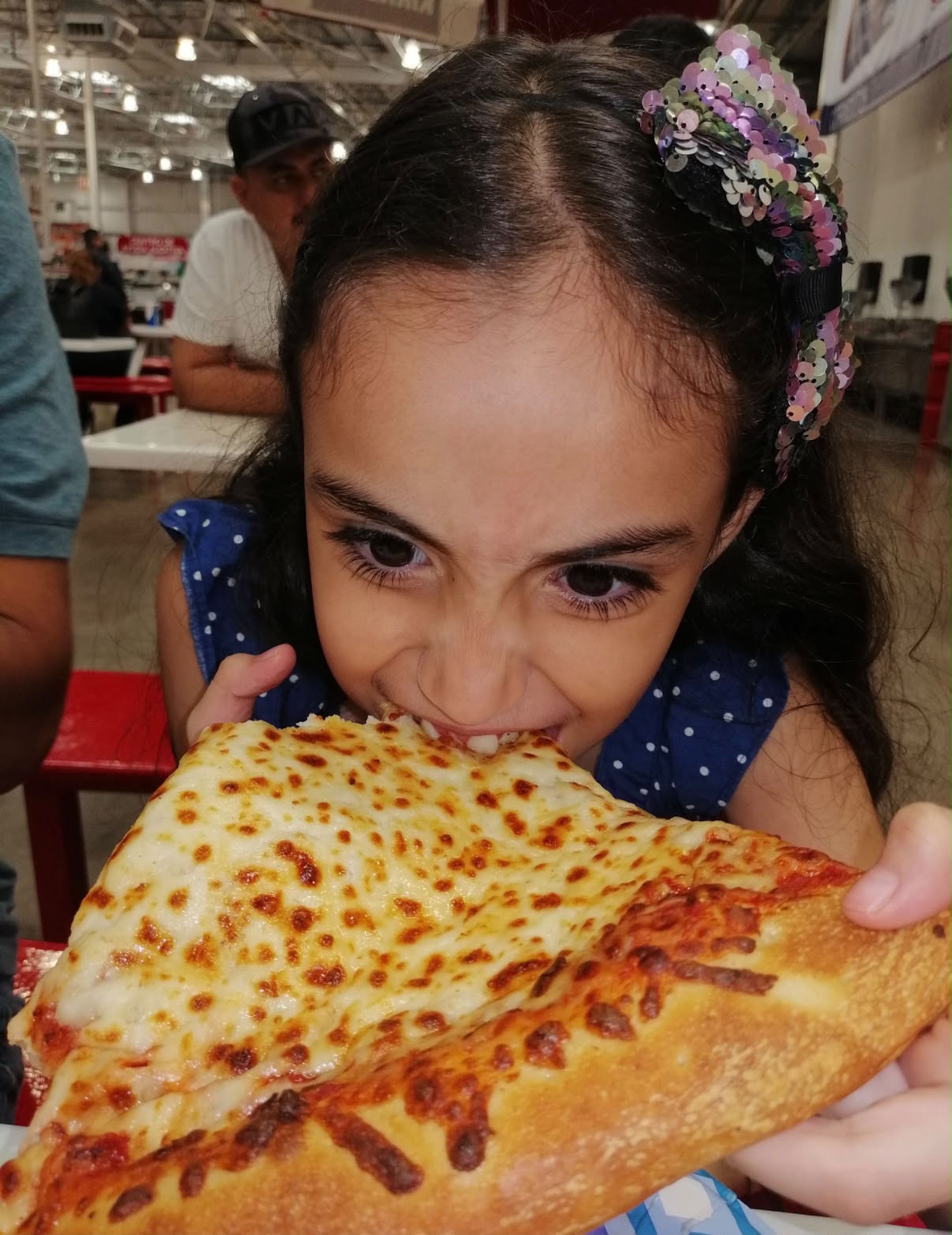 Elsa de niña comiendo una rebanada grande de pizza
